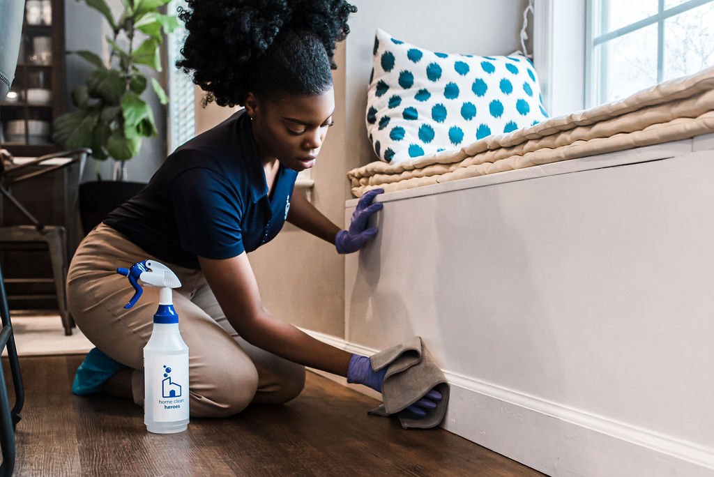 Cleaner wiping down baseboards during home cleaning service